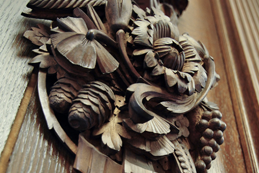 Wood carved plaque with pinecones, flowers, and leaves
